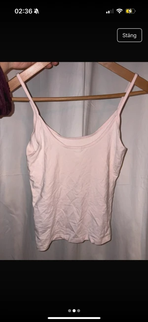 Ljusrosa linnetopp från Gina Tricot - Supersöt ljusrosa linnetopp från Gina Tricot, Elevated Basics. Tunn och mjuk bomull med smala axelband och enkel, rak passform. Perfekt att styla med jeans eller kjol för en chill look.