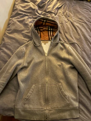 Grå Burberry hoodie med rutig huva - Säljer denna stilrena burberry hoodien då den inte kommer till användning längre, går givetvis att få fler bilder och kan diskutera priset vid snabb affär. Hör av er vid frågor 
