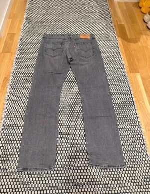 Levi's 501 grå jeans W32 L32 - Säljer ett par Levi's Premium 501 jeans i snygg grå tvätt. Klassisk rak passform med fem fickor och ikonisk läderpatch bak. Jeansen är tillverkade i slitstarkt bomullsjeansmaterial och har en stilren look som funkar till det mesta. Den var en väldigt liten skavank vid bakfickan.
