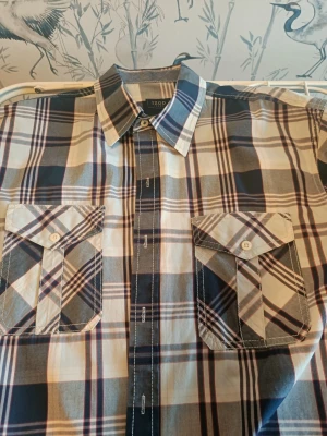 Rutig långärmad skjorta från IZOD - Säljer en snygg rutig skjorta från IZOD Jeans i storlek L. Skjortan har klassisk krage, två bröstfickor med lock och knappar, samt långa ärmar med manschett. Färgerna är blå, grå och vit med inslag av rött. Perfekt för dig som gillar en chill och stilren look.