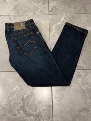 Jacob Cohën jeans - Snygga blå jeans från Jacob Cohën. Jeansen har mörkblå färg som ger en cool look. Märkespatch baktill och broderad J på fickan. Perfekta för dig som gillar stilrena jeans. Storleken är i W32