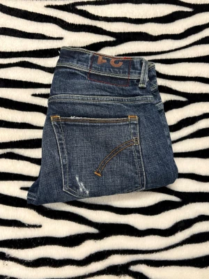 Dondup - Säljer ett par blå jeans från Dondup, modell Konor Skinny Fit. Jeansen har slitna detaljer, synliga sömmar i kontrastfärg och klassisk femficksdesign. Stängs med knappar i gylfen och har en cool, smal passform som sitter snyggt. Hör av dig vid minsta fundering 😌