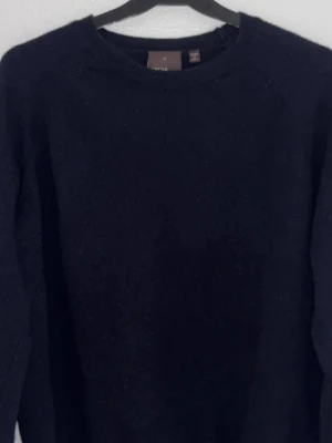 Mörkblå stickad tröja från Oscar Jacobson  - Säljer en enkel och stilren mörkblå stickad tröja från Oscar Jacobson. Tröjan har rund hals och långa ärmar, perfekt för kyliga dagar. Passar dig som gillar klassiska och tidlösa plagg. Snygg att matcha med jeans eller chinos.