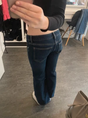 Mörkblå bootcut jeans med låg midja - Snygga mörkblå jeans med klassisk femficksdesign och låg midja. Modellen har bootcut-ben som ger en schysst siluett och är tillverkade i mjukt jeansmaterial. Från H&M Storlek S/36,  knappt använda. 