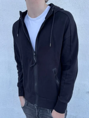 C.P Company hoodie - Säljer denna asfeta hoodie från C.P Company! Skick 8,5/10 - inga defekter. Nypris 2999kr, mitt pris endast 1099kr. Hoodien har de klassiska "glasögonen" på luvan! Hör av er vid funderingar.