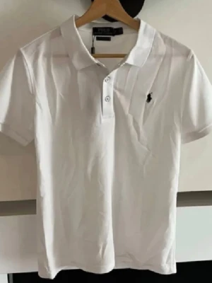 Vit Polo Ralph Lauren Piké  - Säljer denna stilrena, efterfrågade pike från Polo Ralph Lauren. Riktigt utmärkt kvalitet och väldigt snygg som passar allt. Skriv gärna vid intresse och för mer information! Tveka inte på att skicka bud.
