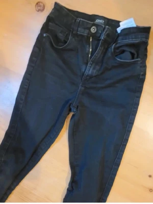 Svarta skinny jeans från ONLY - Säljer ett par svarta skinny jeans från ONLY med hög midja. Jeansen har klassisk femficksdesign, dragkedja och knapp framtill. Materialet är stretchigt och sitter tight längs benen för en snygg siluett. Perfekta till sneakers eller boots. Sparsamt använda. 