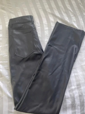 Svarta skinnbyxor från BikBok - Snygga svarta skinnbyxor från BikBok i storlek 38. Byxorna har rak passform och är Mid/highwaist. Knappen ovanför gylfen sitter löst men går lätt att byta ut.                                                                       Kontakta privat vid intresse!🥰