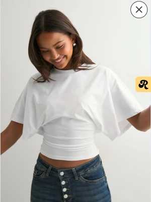 Vit croppad topp med vida ärmar - Säljer en vit croppad topp från Gina tricot med vida, korta ärmar och rund halsringning. Toppen har en tight passform över midjan. Använd max 2 gånger och säljer för att den mest ligger och inte kommer till användning.