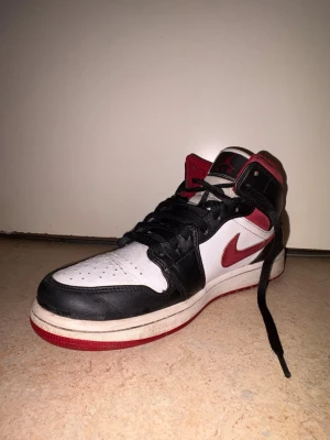 Nike Air Jordan 1 GYM RED - Nike Air Jordan 1 sneakers i klassisk svart, röd och vit färg. Skorna har högt skaft, snörning och rund tå. Swoosh-loggan i rött på sidan och Air Jordan-märket på ankeln. Tillverkade i skinn med platt sula och perforerad tå för extra ventilation. Dom är använda ett par gånger, så helt nya är dom inte men dom har inga stora skavanker så att säga, dom behöver kärlek bara! 