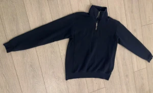 Mörkblå half zip tröja - Snygg mörkblå tröja med half zip och hög krage. Tröjan har långa ärmar och ribbade muddar vid ärmslut och nederkant. Perfekt för dig som gillar enkel och stilren design. Passar till både jeans och mjukisbyxor.