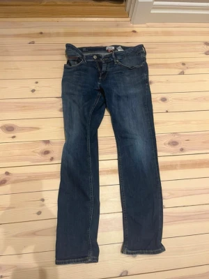 Hilfiger Denim Slim Jeans blå - Snygga blå jeans från Hilfiger Denim i modellen Slim Scanton. Klassisk femficksdesign med gul kontrastsöm och dragkedja. Jeansen har en slim passform och är tillverkade i slitstarkt denim-material. Sitter väldigt snyggt på hör av er vid minsta fråga mvh Nils 😃 