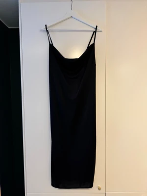 Svart slipklänning  - Silkig slipklänning med slits på ena sidan längst ner och fint fall i urringningen. Lapp bortklippt men är storlek M/38 från HM. Går strax under knäna på mig som är 173cm.