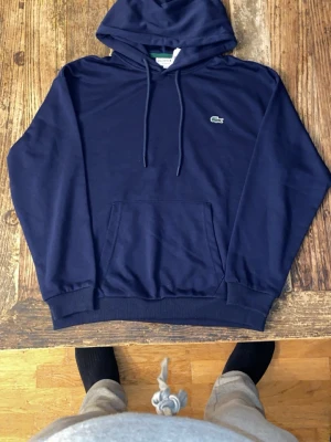 Lacoste hoodie  - Mörkblå Lacoste hoodie i storlek L, helt ny. Pris kan diskuteras. För hjälp med att veta om den kommer att passa skriv till mig så hjälper jag med måtten på tröjan och bild när jag har på mig den.
