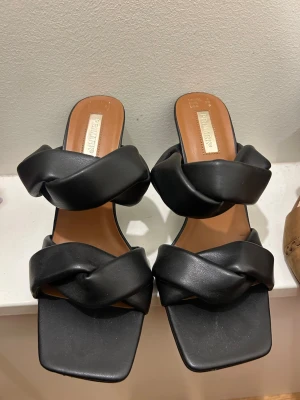 Svarta klackar  - Säljer ett par svarta klackar från Primark i storlek 39. De har breda, flätade remmar i syntetmaterial och fyrkantig tå. Klacken är ca 5 cm och sulan är platt.