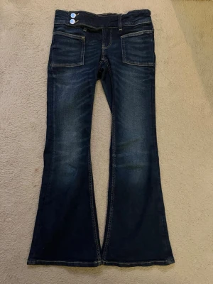 Mörkblå bootcut jeans med dubbla knappar - Säljer ett par justerbara mörkblåa  jeans med bootcut passform ifrån Gina tricot young i storlek 146❤️ inga särskilda fickor, du får betala frakten! nypris: 359kr 