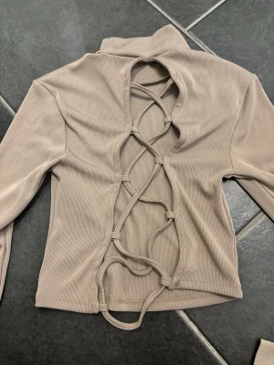 Långarmad tröja med öppen rygg - Långarmad tröja med öppen rygg. Ljusbrun.