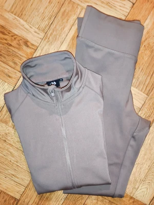 Tränings det strl S - Ett matchande set bestående av en träningsjacka med dragkedja samt fickor och ett par tights. Båda plaggen har en diskret logotyp. Kommer från lager 157 och är använda en gång.   Kom gärna med eget pris förslag