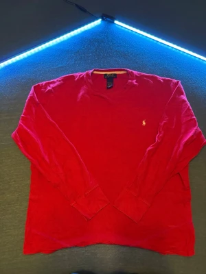 Röd långärmad tröja Polo Ralph Lauren - Riktigt snygg röd långärmad tröja från Polo Ralph Lauren i 100% bomull. Klassisk passform med rund hals och ikoniska broderade loggan på bröstet. Perfekt till chill vardagsstil eller när du vill ha något enkelt men stilrent. Kanske finns någon fläck, går att tvättas ,