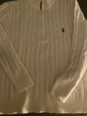 Vit kabelstickad tröja Polo Ralph Lauren S - Säljer en vit kabelstickad tröja från Polo Ralph Lauren med half zip och klassisk logga på bröstet. Tröjan har hög krage, långa ärmar och ribbade muddar. Perfekt för dig som gillar stilrena och tidlösa plagg. Storlek S