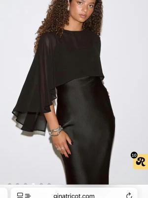 Svart långklänning från Gina Tricot - Supersnygg svart långklänning från Gina Tricot med flowiga, transparenta ärmar och cape-liknande överdel. Slutsåld. Strl 32. Pris 250 kr❤️använd en gång 