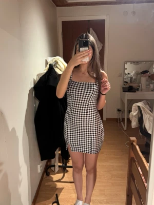 Svartvit rutig kort klänning - Svartvit rutig klänning. Armlos modell med fyrkantig halsringning och liten slits framtill. Knappt använd, som ny!
