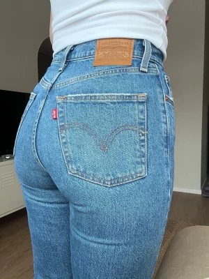 Levi's 501 mellanblå raka jeans, high waist, storlek 26 (nyskick) - Klassiska Levi's 501 jeans i mellanblå tvätt med raka ben och hög midja. Jeansen har knappgylf och är i nyskick. Använda 2 gånger. Säljer pga att jag inte använder höga jeans längre. Fler bilder finns! Nypris: 1.349kr