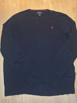 Mörkblå tröja från Polo Ralph Lauren - Säljer en mörkblå långärmad sweatshirt från Polo Ralph Lauren i mjuk pima bomull. Klassisk rund halsringning och röd broderad logga på bröstet. Perfekt till chill outfits och enkel att matcha med jeans eller chinos.        Passar som storlek S, barn (18-20) därav står det (XL) på etiketten 