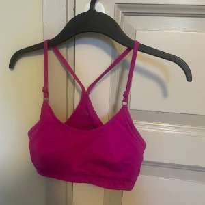 Rosa sport BH  från Casall S - Säljer en snygg rosa sportväst från Casall i storlek S. Västen har tunna, justerbara axelband som korsas i ryggen och en liten logga framtill. Tillverkad i ett stretchigt syntetmaterial som passar perfekt till träning.