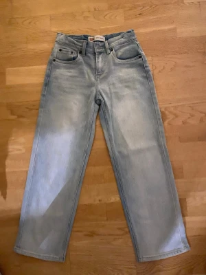 Levi's Stay Loose ljusblå jeans - Säljer ett par Levi's Stay Loose jeans i ljusblå tvätt. De har en loose passform med raka ben och klassiska fem fickor. Jeansen är tillverkade i bomull och har en hög midja. Perfekta för en avslappnad och trendig look.