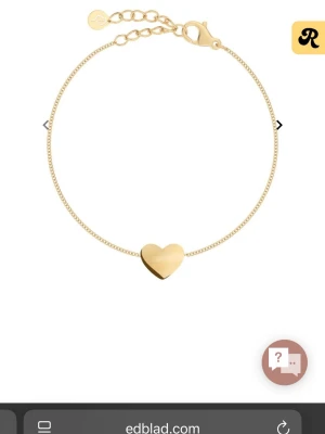 Guldarmband med hjärta från Edblad - Snyggt och stilrent armband i guldpläterat stål från Edblad. Armbandet har en tunn kedja och ett litet hjärta i mitten som ger en söt och modern look. Justerbar längd med karbinlås och liten logoberlock vid låset.