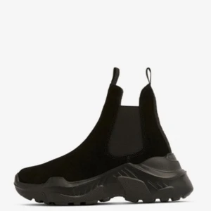 Chunky Svea evil boot svarta chelsea boots - Säljer ett par chunky svarta chelsea boots med bred resår på sidorna och grov sula. Boots i mocka-look med rund tå och dragflikar både fram och bak. Perfekta för dig som vill ha en edgy och trendig stil. 1499 kr nypris 