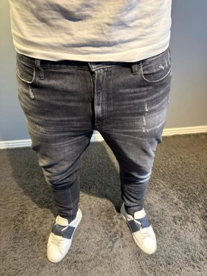 Dondup jeans - Säljer ett par mörkgrå dondup jeans med slitningar. Jeansen har en slim passform. Storlek w31. Modellen på bilden är 184cm.