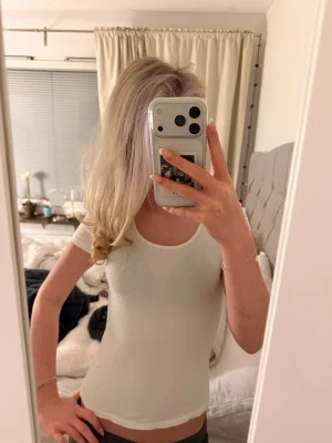 Vit tight t-shirt med rund hals - Säljer en enkel och stilren vit t-shirt med rund halsringning och korta ärmar. Modellen är tight och figurnära, perfekt att matcha med jeans eller kjol. Materialet känns mjukt och stretchigt, vilket gör den riktigt bekväm att bära.