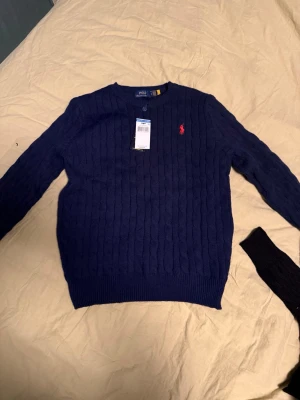 Mörkblå kabelstickad tröja Polo Ralph Lauren - Säljer Ralph Lauren-tröjor eftersom jag har många hemma och inte vet vad jag ska göra med dem. Därför har jag valt att sälja dem billigt. För dig som vill ha en tröja av bra kvalitet. Vill sälja snabbt. Tröjorna är oanvända. Storlek M