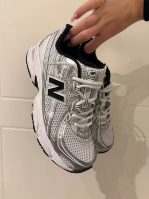 Vita New Balance sneakers med silverdetaljer - Säljer ett par snygga New Balance sneakers i modellen 740. Endast använda tre gånger. Nypris 1500kr. Pris kan diskuteras. Kommer utan box därav priset