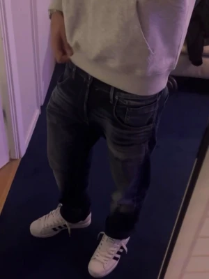 Jack & Jones blå jeans med slitningar - Säljer ett par blå jeans från Jack & Jones med snygga slitningar och tvättade detaljer. Klassisk femficksmodell med normal passform och raka ben. Hör av dig vid frågor:)