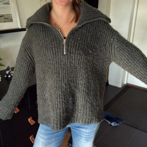 Mörkgrön stickad Weekday half zip tröja - Säljer en mörkgrön stickad tröja från Weekday i storlek M. Tröjan har en bred krage och half zip-dragkedja framtill. Den är ribbad och har långärmade, loose passform som ger en chill och avslappnad vibe. Perfekt för kalla dagar när du vill vara både bekväm och snygg.