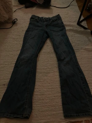 Bootcut jeans - Blåa lågmidjade bootcut jeans från Ellos. Storlek 26/32, passade mig som hade Xxs/xs. De har ett litet hål längst ner vid på benet (se bild 4).