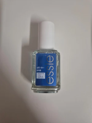 Essie all-in-one base & top coat - Essie all-in-one base & top coat i genomskinlig formula. Kommer i en fyrkantig glasflaska med vit plastkork och blå etikett. Innehåller 13,5 ml och funkar både som baslack och överlack för naglarna.