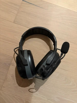 Hellberg Xstream LD headset med mikrofon - Säljer ett par svarta Hellberg Xstream LD over-ear headset med inbyggd mikrofon och aktiv lyssning. Robust design med vadderad bygel och stora kåpor. Perfekt för gaming eller kommunikation där du behöver både ljud och mikrofon.