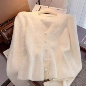 Vit fluffig kofta med pärlknappar - Supermjuk och fluffig vit kofta med v-ringning och pärlknappar framtill. Koftan har lång ärm och är stickad i ett mysigt material som känns lyxigt. Perfekt att slänga på sig när du vill vara både bekväm och snygg. Bara testad. Säljer den då den var för stor för mig.