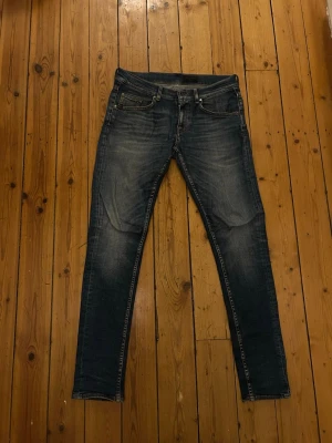 Tiger of sweden jeans - Snygga Tiger of sweden jeans i mörkblå tvätt med klassisk femficksdesign och diskreta slitningar. Modellen har smal passform och normal midja, perfekt för en stilren och modern look. Ikonisk läderpatch bak i midjan och dragkedjegylf.