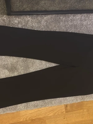 Svarta byxor  från Bik Bok - Säljer ett par klassiska svarta utsvängda byxor  från Bik Bok i storlek M. De har en tight passform och är tillverkade i ett mjukt och stretchigt material som sitter skönt hela dagen. Perfekta att matcha med oversized tröjor eller hoodies.