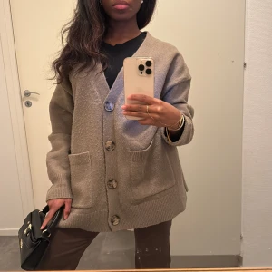Oversized kofta med stora knappar - Beige oversized kofta med stora knappar och två stora fickor framtill. Koftan har lång ärm, v-ringning och är stickad i ett mjukt material. Nopprig🎀