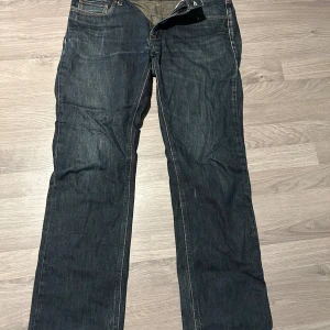 Acne Jeans - Säljer ett par mörkblå jeans från Acne med klassisk femficksdesign och raka ben. Jeansen har normal passform och är tillverkade i slitstarkt denimtyg. Perfekta till sneakers eller boots för en clean look.