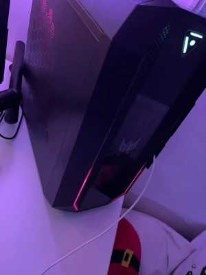 Acer Predator stationär gamingdator  - Snygg stationär dator från Acer Predator-serien med svart chassi, RGB-belysning och coola hexagonmönster på sidan. Fronten har genomskinligt fönster och upplysta detaljer. Perfekt för gaming och streaming med modern design. GTX 1660 / i5–