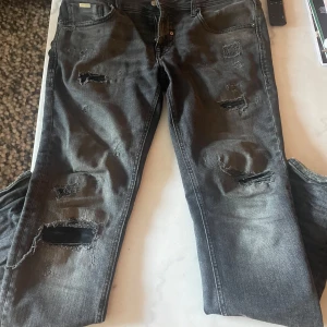 Svarta slitna jeans från Antony Morato - Säljer ett par svarta jeans från Antony Morato med snygga slitningar. Jeansen har klassisk femficksdesign. Perfekta för dig som gillar en trendig look. Köpte för 1899kr, pris kan diskuteras