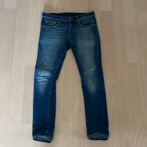 Blå dondup George jeans herr - Snygga blå jeans från Replay, modell Anbass. De har en klassisk femficksdesign, dragkedjegylf och smal passform. Jeansen har slitningar och snygga tvättade detaljer för en cool look. Perfekta för dig som gillar stilrena och moderna jeans.