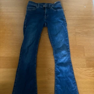 Blå low flare jeans XS - Snygga blå jeans med låg midja och flare-ben. Modellen är low flare och har klassisk femficksdesign. Perfekta för dig som gillar en retroinspirerad look med utsvängda ben. Jeansen är i denim och passar till många olika stilar.